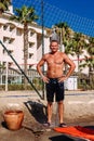 Tanned man in shorts standing under a cold shower on the beach in summer Royalty Free Stock Photo