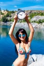 Tanned smiling girl in swimsuit on a mountain lake holding watch Royalty Free Stock Photo