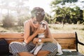 Tanned smiling lady in elegant wristwatch embracing beagle dog during rest in park in morning, Charming woman in