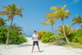 Tanned tall handsome man wearing white t-shirt and black shorts standing at tropical sandy beach at island luxury resort Royalty Free Stock Photo