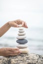 Tanned woman hands stacked pebble stones tower on sea beach relaxing harmony summer travel vacation Royalty Free Stock Photo