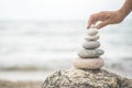 Tanned woman hands stacked pebble stones tower on sea beach relaxing harmony summer travel vacation Royalty Free Stock Photo