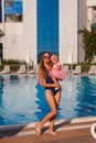 Tanned woman in swimsuit hugs baby girl