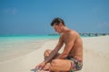 Tanned young attractive man near ocean in swimming wear at tropical beach at island luxury resort Royalty Free Stock Photo