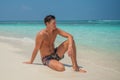 Tanned young man near ocean in swimming wear at tropical beach at island luxury resort Royalty Free Stock Photo
