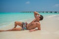 Tanned young man resting near ocean in swimming wear at tropical beach at island luxury resort Royalty Free Stock Photo