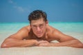 Tanned young sexy handsome male model enjoying sun bathing near ocean at tropical sandy beach at island luxury resort Royalty Free Stock Photo