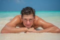 Tanned young sexy male model enjoying sun bathing near ocean at tropical sandy beach at island luxury resort Royalty Free Stock Photo