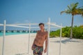 Tanned young sexy man standing near ocean in swimming wear at tropical beach at island luxury resort Royalty Free Stock Photo