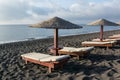 Tanning beds and umbrellas on Perissa beach, Santorini island, Greece. Royalty Free Stock Photo