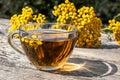 Tansy infusion in a glass cup on a wooden table. Tansy Herbal tea. Healing herbs