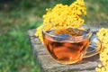 Tansy infusion in a glass cup on a wooden table. Tansy Herbal tea. Healing herbs
