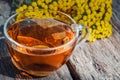 Tansy infusion in a glass cup on a wooden table. Tansy Herbal tea. Healing herbs