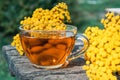 Tansy infusion in a glass cup on a wooden table. Tansy Herbal tea. Healing herbs