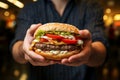 A tantalizing close up of a beefy burger gripped by a mans hungry hands