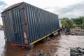 TANZANIA, ARUSHA - JAN 2020: Heavy Cargo Truck Stuck in the River. Maasai people Standing on the Shore. Ford at African