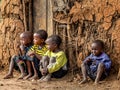 Group of Masai children are sitting near a traditional clay house.