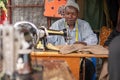 TANZANIA, MASAI VILLAGE - JANUARY 2020: Portrait of Sewer of Swiss Tailor Maasai man working With sewing machine in