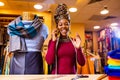 tanzanian woman with snake print turban over hear working in fabrics shop calling to client by smartphone