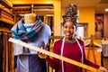 tanzanian woman with snake print turban over hear working in fabrics shop with ruler Royalty Free Stock Photo