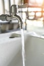 Tap water running wastage from faucet over hand washing sink for saving ecological