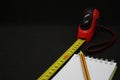 Tape measure pencil and notepad on a dark background Royalty Free Stock Photo