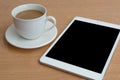 Taplet with black screen and coffee cup on wooden desk Royalty Free Stock Photo