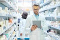 Tapped into the latest pharmaceutical brands. a mature man using a digital tablet to do inventory in a pharmacy. Royalty Free Stock Photo