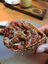 Tar-tar made of sliced beef with onion and pickles served in a round waffle.