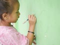 A girl is engrossed in drawing on a green wall