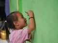 A girl is engrossed in drawing on a green wall