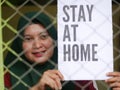 An Indonesian woman isolating at home. She is hoding campaign paper for coronavirus prevention