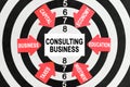 On the target arrows with business lettering point to the center on a business card with the inscription - CONSULTING BUSINESS