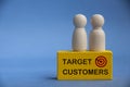 Target customers text on yellow wooden block with model wooden dolls on top. Business and marketing concept Royalty Free Stock Photo