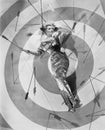 A target of desire, a young woman lying on the bulls eye with arrows around her