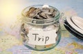 Target for travel - concept saving money in a glass and word `trip` on map.