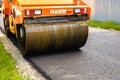 Targoviste, Romania - 2019. Close up photo of an orange road roller compacting the new asphalt. Construction of a new road with