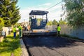 Targoviste, Romania - 2019. Close view on workers operating asphalt paver machine during road construction. Construction of a new
