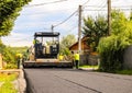 Targoviste, Romania - 2019. Workers operating asphalt paver machine during road construction on a sunny day. Construction of a new