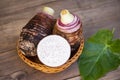 Taro root with slice half on basket and taro leaf and wooden background, Fresh raw organic taro root ready to cook Royalty Free Stock Photo