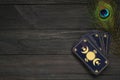 Tarot cards and peacock feather on black wooden table, flat lay with space for text. Reverse side Royalty Free Stock Photo