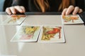 Tarot cards, Tarot card divination, esoteric background. A woman makes a layout on the cards at the table. Divination