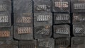 Tarred black railway sleeper wooden beam with nail plates and cracks at ends, stacked in rows in stack. Industrial background.