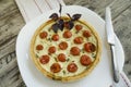 Tart with cherry tomatoes, cheese and onions on white plate, near knife Royalty Free Stock Photo