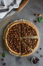 Tart with chocolate caramel, hazelnuts, peanuts, almonds and seed mix on a dark concrete background. Vertical orientation. Royalty Free Stock Photo