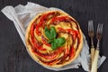 Tart with eggplants and tomatoes decorated with fresh basil leaves and two forks. Homemade vegetable pie on the black wooden table Royalty Free Stock Photo