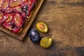 Tart or pie with plums and plum halves on wooden rustic background. Top view Royalty Free Stock Photo