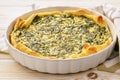 Tart with spinach and eggs on white background.