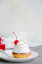 Tartalet with cherry filling and Italian meringue with a cocktail cherry on top on a white plate Royalty Free Stock Photo