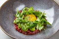Tartare with egg, green beans, herbs and spices in gray bowl
